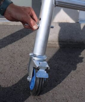 man houd een borgclip vast om een wiel te bevestigen aan een kamersteiger