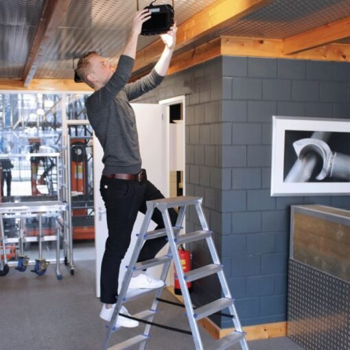 Man staat op een alumexx dubbele trap om een lamp te bevestigen aan het plafond
