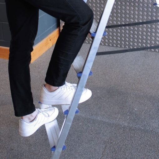 Man met witte sneakers loopt een Alumexx dubbele trap op.
