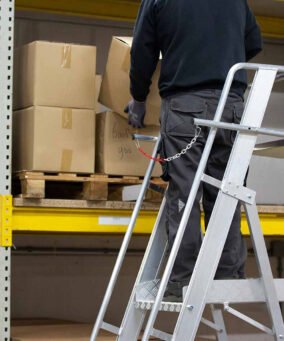 Man staat op een eurostairs magazijntrap easy te werken in een magazijn